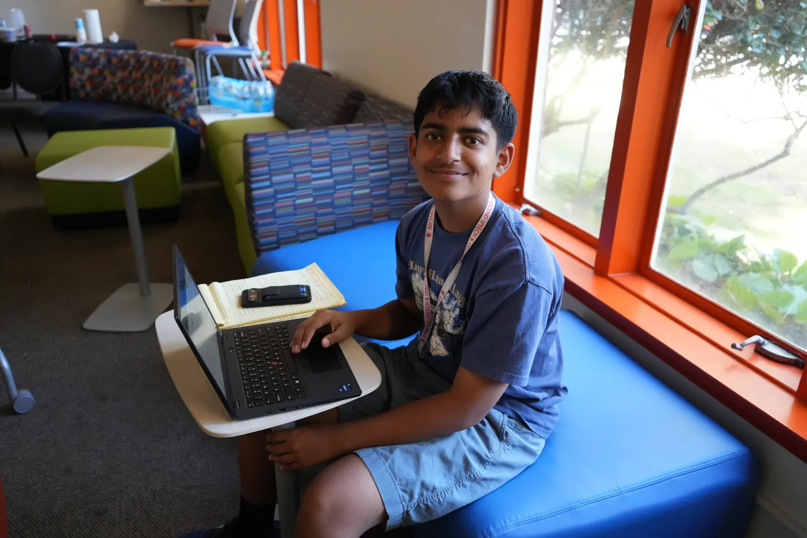 A student working on a laptop by a sunny window